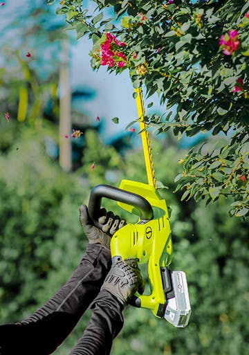 Sun Joe 24-volt cordless hedge trimmer kit being used to trim hedges.
